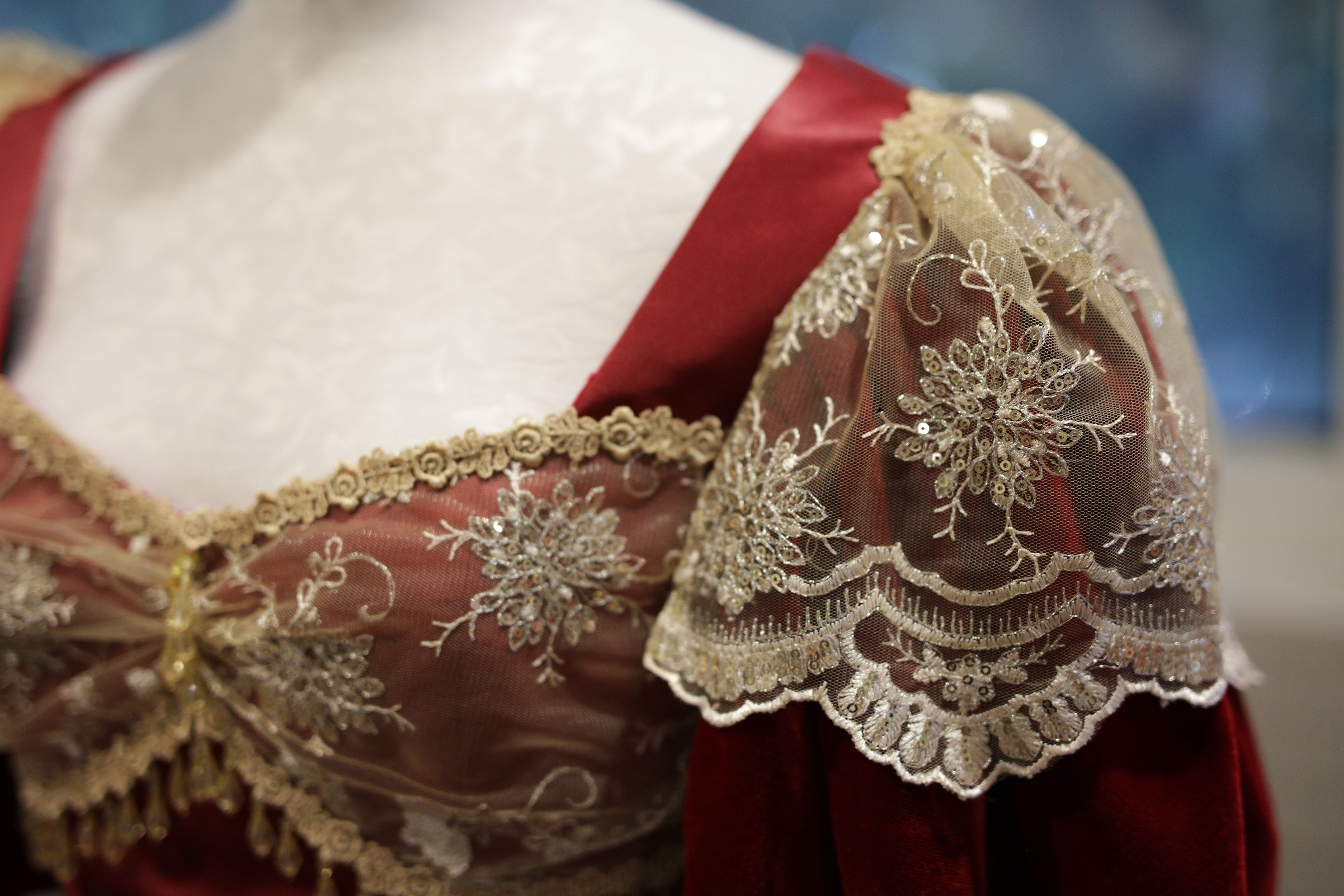 Close up of a red bodices with lace on sleeves, displayed on a mannequin. Photo by Art Andrews.